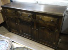 An oak dresser base having three drawers across and three ogee field panel doors below on stile feet