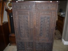 An Indian hardwood wardrobe having two panelled doors all over carved with plant forms, interior