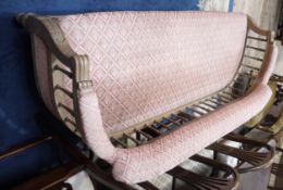A late Victorian beech framed occasional sofa having a curved frame and spindle back, upholstered