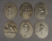 A set of six Art Deco silvered metal oval sports plaques, 1930s, worked in relief with scenes of