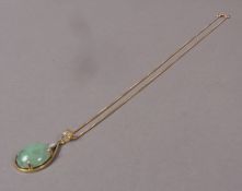 A jade and diamond pendant, the oval cabochon jade claw set within a pear shaped surround below