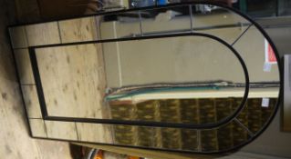 A wall mirror of arched outline