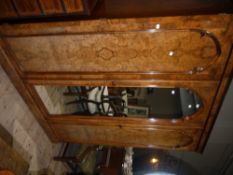 A Victorian figured walnut three door wardrobe having a moulded cornice above a central mirrored