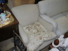 An Edwardian Howard style upholstered armchair, upholstered in oatmeal linen, on square tapered legs