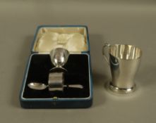 A child's silver egg cup, spoon and napkin ring set, engraved with a bird, in a fitted case,