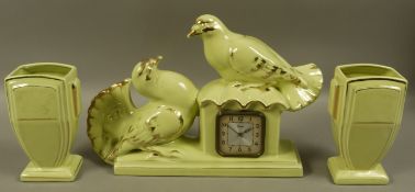 An Art Deco style green glaze clock garniture, the clock surmounted with fantailled doves and two