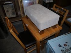 A small pine dining table and a pair of chairs together with a modern footstool and a magazine rack
