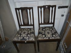 A pair of Edwardian mahogany dining chairs with bergere caned panel backs