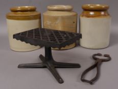 A cast iron trivet, pair of sugar cutters and three stoneware storage jars