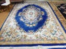 A BLUE GROUND CHINESE FLORAL PATTERNED CARPET, approximate size 370cm x 270cm and a small oatmeal