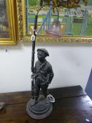 A BLACK PAINTED CAST SPELTER FIGURAL TABLE LAMP, 'Boy with hands in pockets under streetlamp',