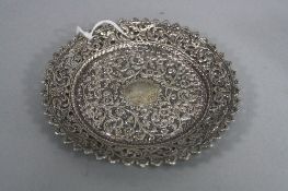 AN INDIAN WHITE METAL CIRCULAR DISH, with wavy edge, foliate pierced and embossed border, the centre