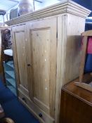 A LARGE PINE PANELLED TWO DOOR WARDROBE, above a single long drawer, approximate size width 150cm