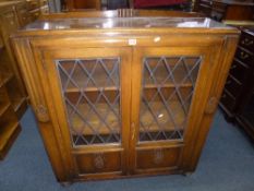 A CARVED OAK LEAD GLAZED TWO DOOR BOOKCASE (key)
