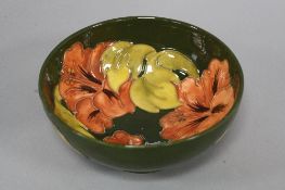 A MOORCROFT POTTERY FOOTED BOWL, Hibiscus pattern on green, impressed and painted marks to base,