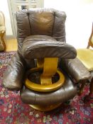 A 'EKORNES STRESSLESS' BROWN LEATHER RECLINING SWIVEL CHAIR, and matching stool (sd, wear, etc)