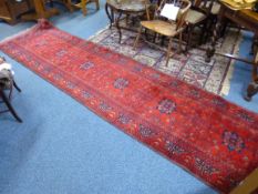 A RED GROUND CARPET RUNNER, approximate size 390cm x 97cm