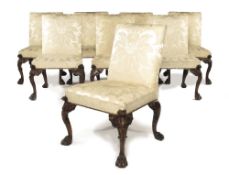 A set of eight walnut side chairs in George II style, each with a padded back and seat upholstered