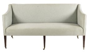 A three seater sofa, with downswept arms on mahogany supports to brass caps and castors, George