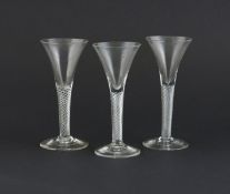 Three wine glasses, 18th century, with drawn trumpet bowls rising from thick airtwist stems, 17.5cm.