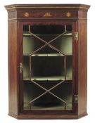 A George III mahogany hanging corner cupboard, the frieze inlaid later paterae and a conch shell