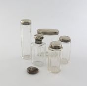 A small collection of five silver mounted glass toilet jars, various dates and makers, plus a silver