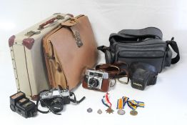 A Minolta “X-300” camera with various accessories; an Agfa camera with leather case; a tan leather
