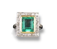 An emerald and diamond cluster ring, the rectangular shaped emerald is millegrain set within a