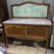 An Edwardian mahogany washstand having a tiled back of arched outline,