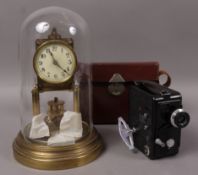 A gilt metal torsion clock underneath a glass dome,