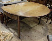 An Edwardian pale mahogany Pembrooke dining table having oval drop leaves,