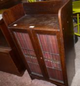 A oak and leaded glazed two door bookcase with three quarter gallery containing an uniform volume