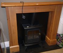 An electric stove style fire in integral pine fire surround