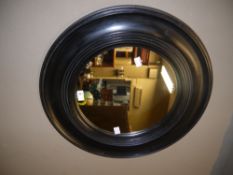 An ebonised circular framed wall mirror with reeded slip