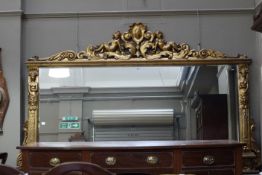 A large gilt framed overmantle mirror having a cherub shield and acanthus cresting,