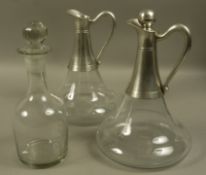 A pair of pewter mounted and clear glass ships decanters, one missing a stopper,