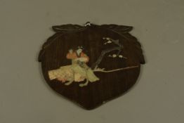 A Japanese peach shaped wood panel inset with hard stones depicting a Bijin sewing beside a blossom